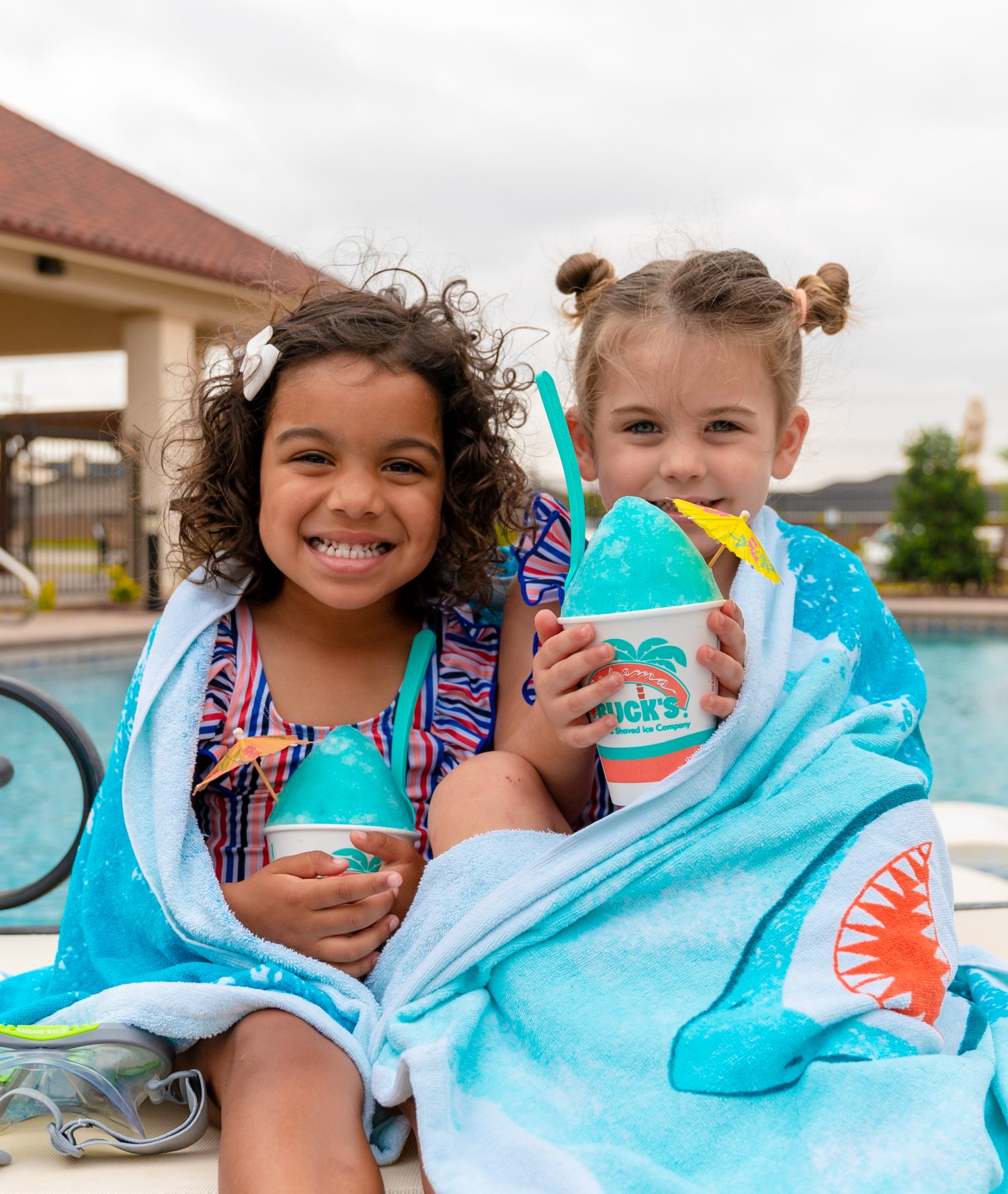 Two girls by the pool enjoying the Shark Attack Sno from Bahama Buck's.