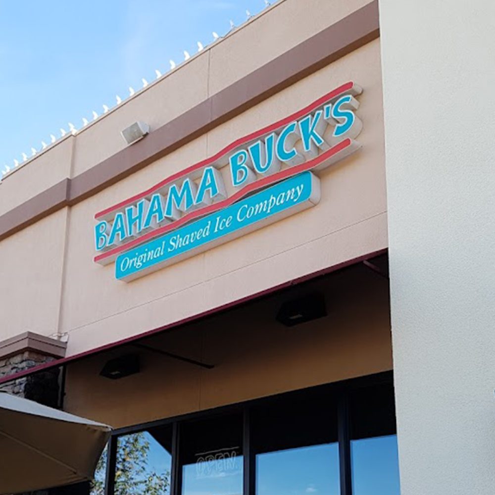 Photo showing the front Bahama Buck's sign, written in blue text, on the building of the Bahama Buck's shop in Redlands, California.